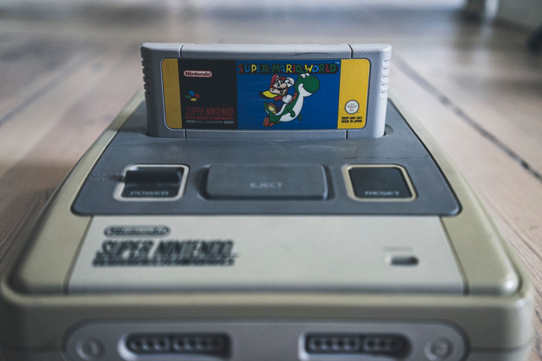 Console de jeu vidéo vintage avec cassette avec autocollant brillant sur la surface sur un sol en bois.