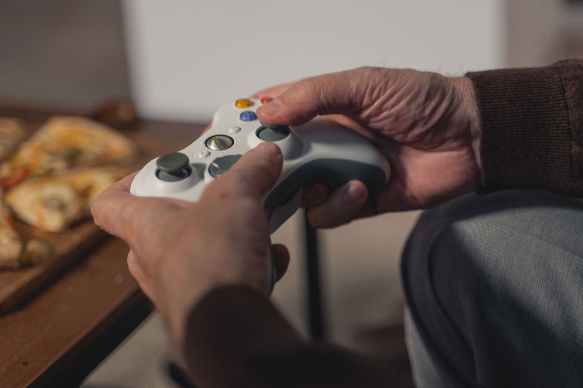 Une personne âgée tenant une manette de jeu, profitant d'un moment de loisir à l'intérieur.